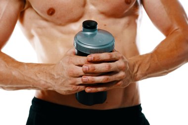 Şişirilmiş gövdesi olan atletik bir adam. Spor tükürüğü şişesi içiyor.