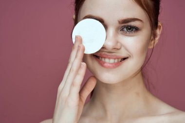 Çıplak omuzlu kadın pamuk pedleri saf ten cazibesi pembe arka plan