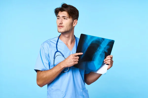Tıbbi üniformalı bir adam. Sağlık tedavisi. Röntgen incelemesi mavi arka plan. — Stok fotoğraf