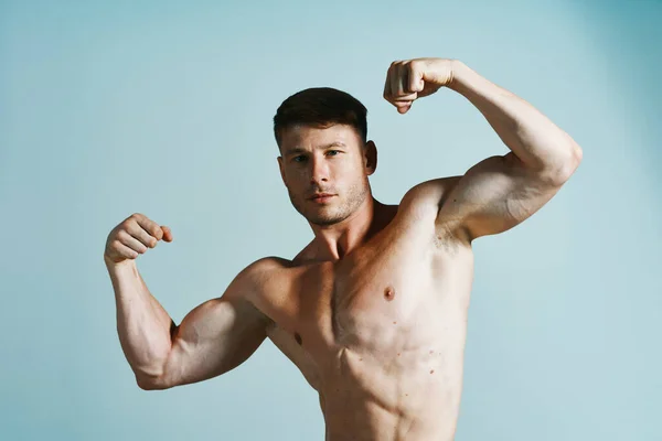 Bodybuilder med muskulös kropp poserar press blå bakgrund — Stockfoto