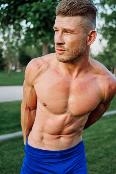 Sporty muscled man with naked torso in a workout park — Stock Photo, Image