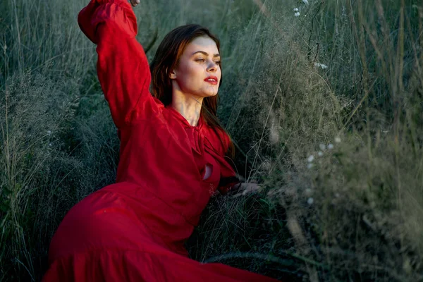 Pretty woman in red dress lies on the grass nature sun — Stock Photo, Image