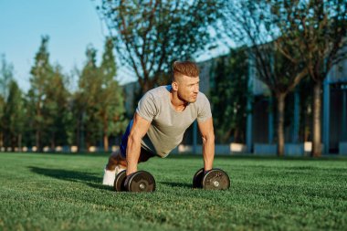 Atletik adam sabah halterlerle antrenman yapıyor. Park.