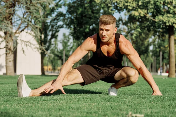 Sportif homme faire des exercices sur la pelouse dans le parc — Photo