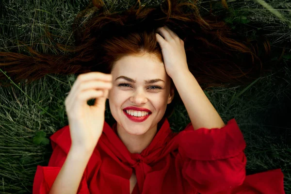 Donna in un abito rosso si trova sull'erba moda natura estate — Foto Stock