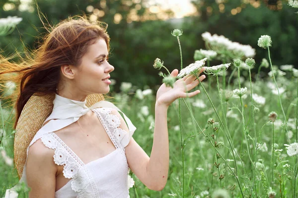 Vacker kvinna i vit klänning i ett fält blommor natur — Stockfoto
