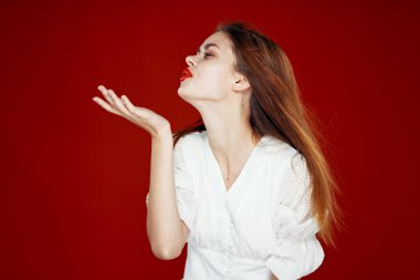 Kırmızı dudaklı neşeli kızıl saçlı kadın. Beyaz elbise. Kırmızı arka plan.