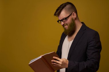 Gözlüklü bir iş adamı, bir stüdyo görevlisinin elinde not defteri.