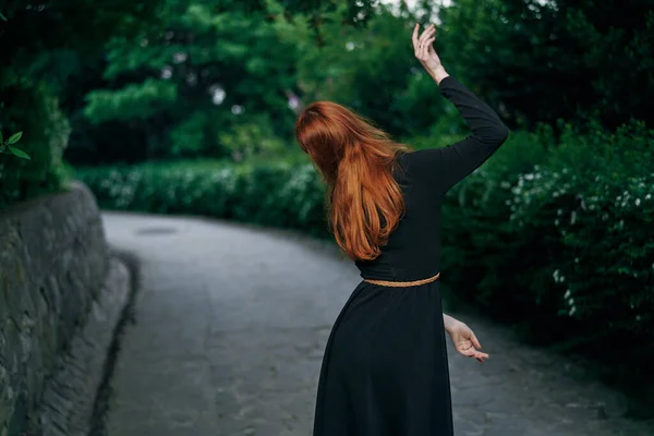 黒のドレスの女性自然の中を歩く庭の木新鮮な空気 — ストック写真