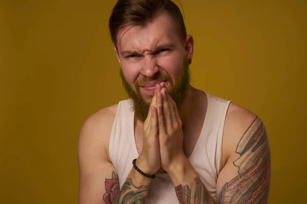 Vousatý muž s vážným výrazem v bílém tričku s tetováním na pažích — Stock fotografie
