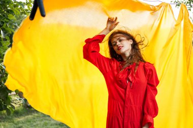 Sarı kumaşın yanındaki kadınlar kırmızı elbise giyerler.