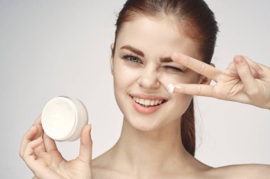 Bir kavanoz krem makyajlı kadın cilt bakımını yakından yapar.