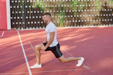 Atletik erkekler yazın spor sahasında egzersiz yapıyorlar.