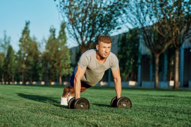 Atletik adam sabah halterlerle antrenman yapıyor. Park.