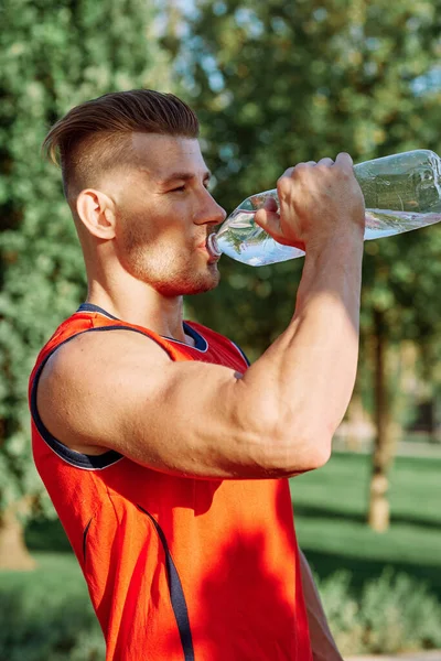 Athletic man with dumbbells in his hands outdoors in the park — Stock Photo, Image