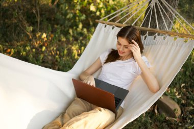 Kadınlar hamakta dizüstü bilgisayarlı tatil internetleriyle yatıyor.
