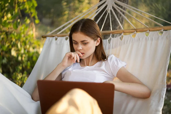 Kobieta pracuje przed laptopem w hamaku w naturze — Zdjęcie stockowe