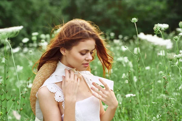 Vacker kvinna i vit klänning i ett fält blommor natur — Stockfoto