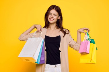 Neşeli kadın, çok renkli. Duygularını alışverişe taşıyor. Moda sarı arka plan.