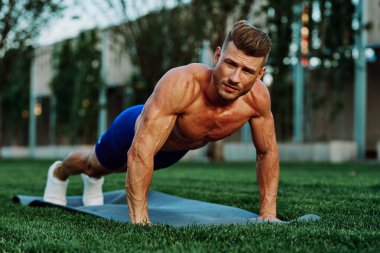Parkta spor yapan kaslı vücutlu bir sporcu.