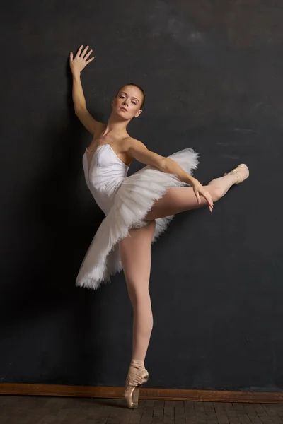 하얀 턱시도 춤을 추는 여성 발레리나의 어두운 배경 공연 — 스톡 사진