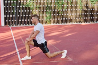 Atletik erkekler yazın spor sahasında egzersiz yapıyorlar.