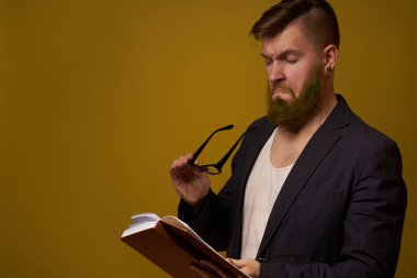 Siyah ceketli sakallı bir adam, elinde bir kitapla.