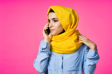 tesettürlü Müslüman kadın telefon iletişim teknolojisi pembe arka plan