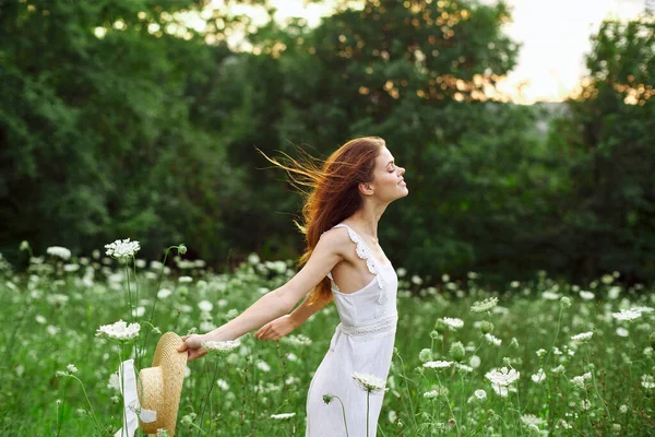 Donna in abito bianco cappello che tiene fiori natura passeggiata — Foto Stock