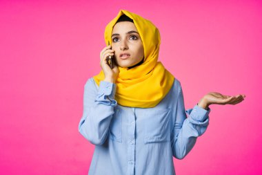 tesettürlü Müslüman kadın telefon iletişim teknolojisi pembe arka plan