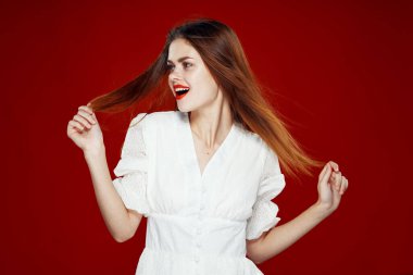 Kırmızı dudaklı neşeli kızıl saçlı kadın. Beyaz elbise. Kırmızı arka plan.