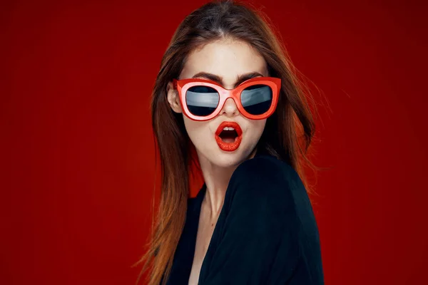 Красивая женщина в солнцезащитных очках мода позировать прическа красный фон — стоковое фото