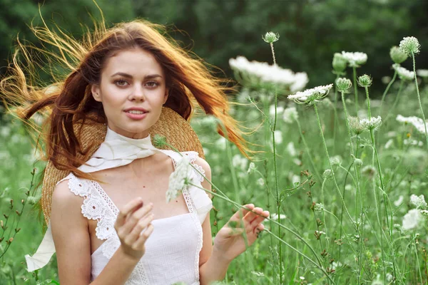 Vacker kvinna i vit klänning i ett fält blommor natur — Stockfoto
