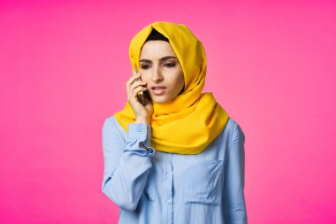 tesettürlü Müslüman kadın telefon iletişim teknolojisi pembe arka plan