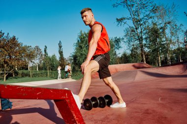 Kırmızı formalı sporcu vücut geliştirme egzersizi yapıyor.