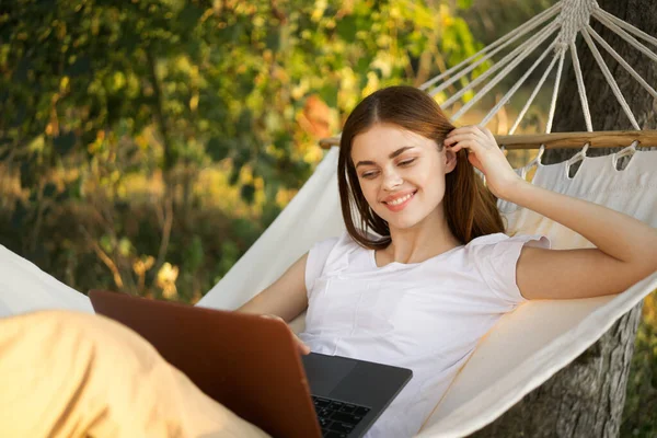 Kobiety na zewnątrz leży w hamaku z laptopem freelance internet — Zdjęcie stockowe
