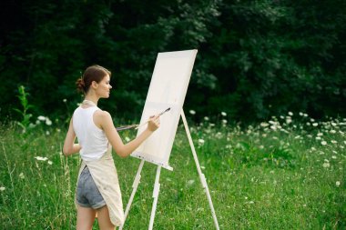 Resim paleti olan kadın ressam doğa hobisi çiziyor.