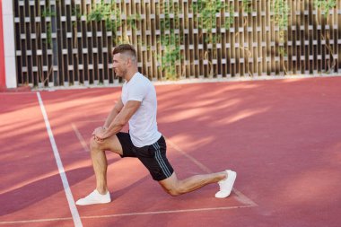 Atletik erkekler yazın spor sahasında egzersiz yapıyorlar.