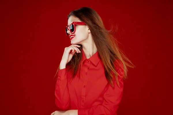 Atractiva mujer en camisa roja gafas de sol moda fondo rojo — Foto de Stock