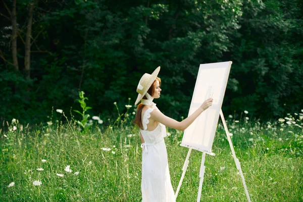 Γυναίκα σε λευκό φόρεμα στη φύση ζωγραφίζει μια εικόνα ενός χόμπι τοπίο — Φωτογραφία Αρχείου