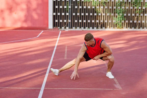 Atletický muž v červeném dresu na sportovním pozemním cvičení — Stock fotografie