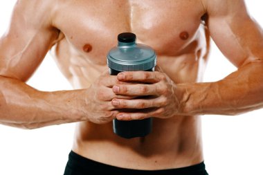 Şişirilmiş gövdesi olan atletik bir adam. Spor tükürüğü şişesi içiyor.