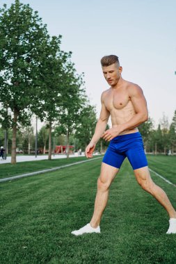 Parkta vücut egzersizi yapan atletik bir adam.