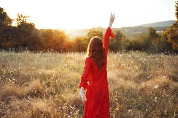 Kobieta w czerwonej sukience w polu chodzić wolność krajobraz — Zdjęcie stockowe