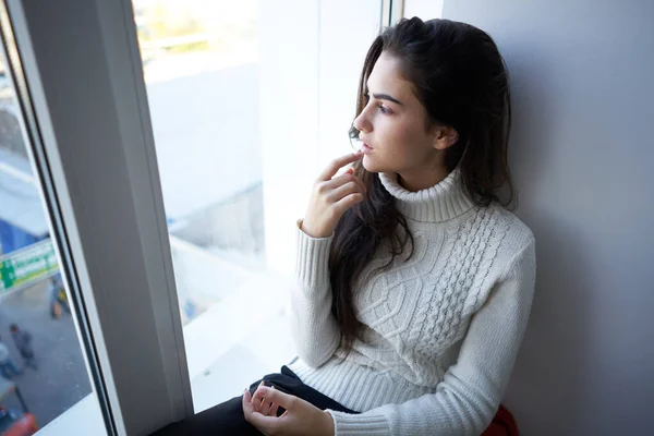 Pretty woman in white sweater near the window — Stock Photo, Image