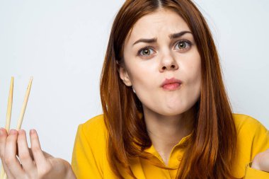 Japon yemek çubuklarıyla suşi yiyen kadın arka planda ışık yayıyor.