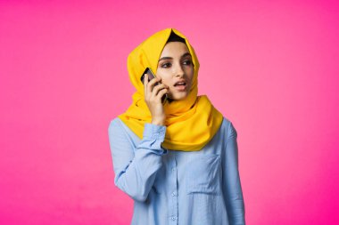 tesettürlü Müslüman kadın telefon iletişim teknolojisi pembe arka plan
