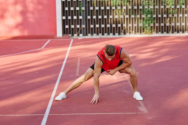 Atletický muž v červeném dresu na sportovním pozemním cvičení — Stock fotografie
