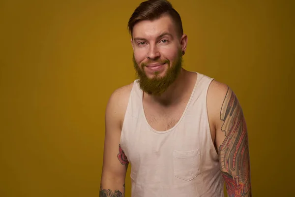 Cheerful bearded man in a white T-shirt with hooligan tattoos on his arms — Stock Photo, Image