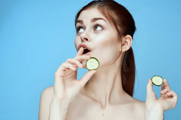 Kvinna med bara axlar gurka vitaminer hälsa blå bakgrund Stockbild